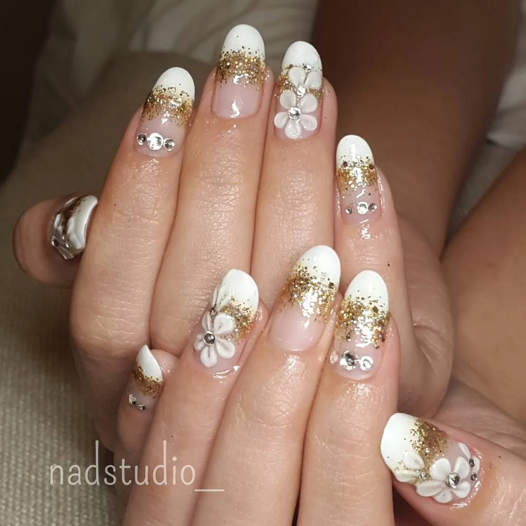 White-and-gold glitter tips with rhinestones and raised floral accents