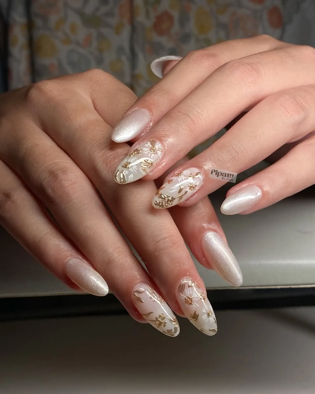 Pearly white stiletto nails with white-and-gold floral accent nails