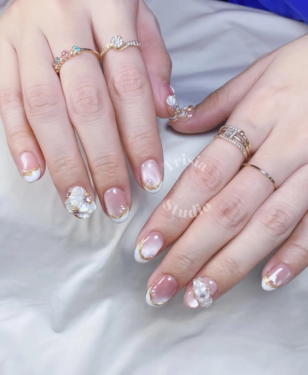 Nude-pink French tips with gold edging and 3D floral accents
