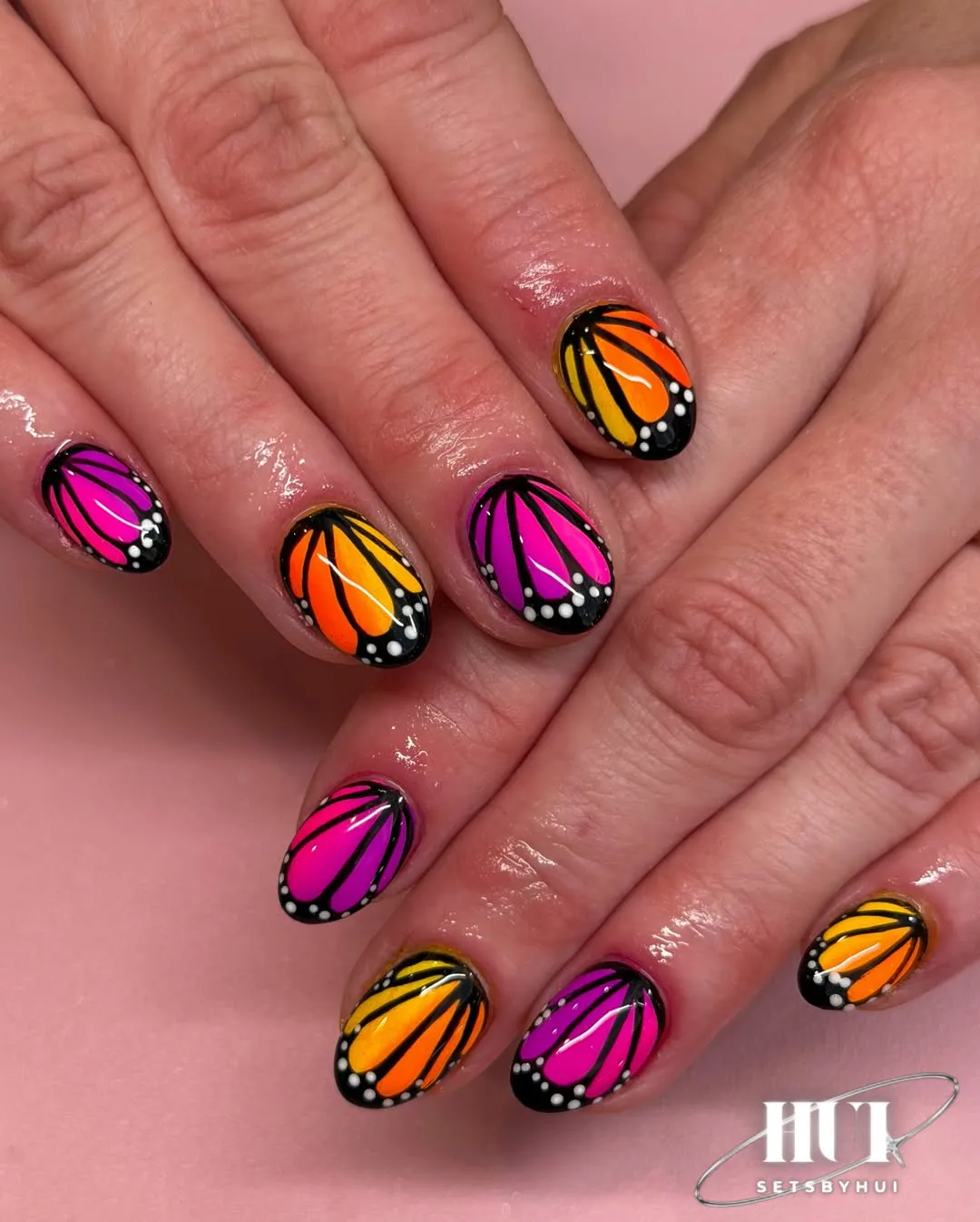 Neon butterfly-wing nail art with black-and-white dotted tips