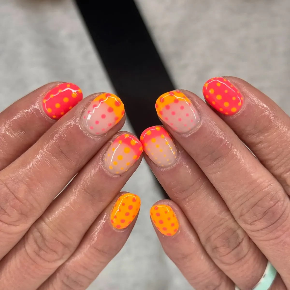 Short neon polka-dot nails in orange and pink