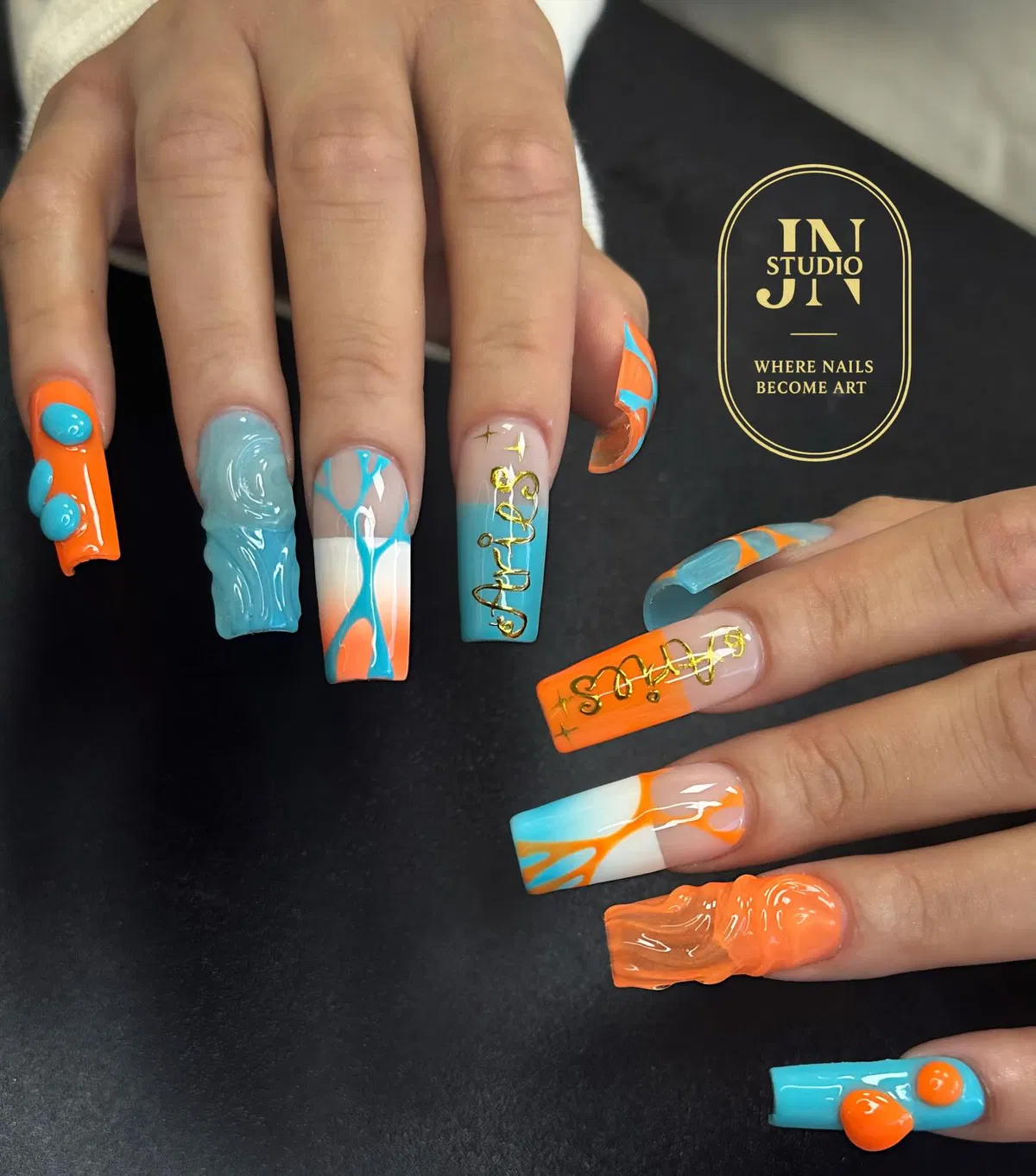 Orange and turquoise 3D nail art with gold script lettering