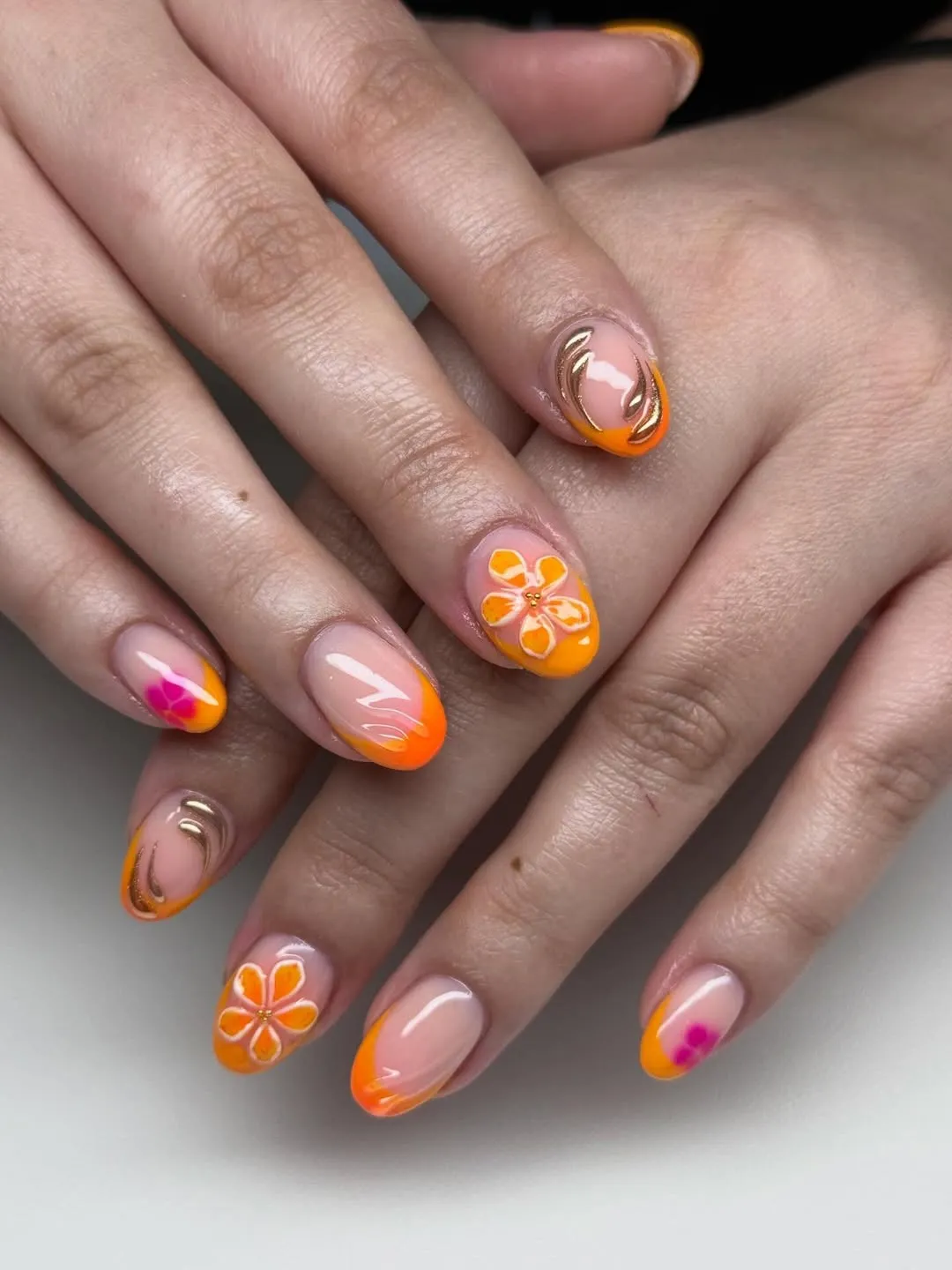 Orange French tips with gold curves and floral accents