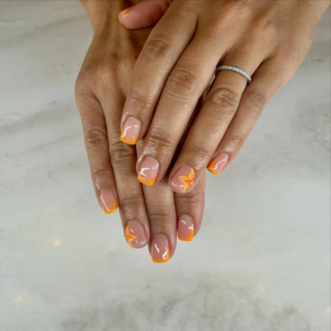 Minimal thin orange French tips with a small flower accent
