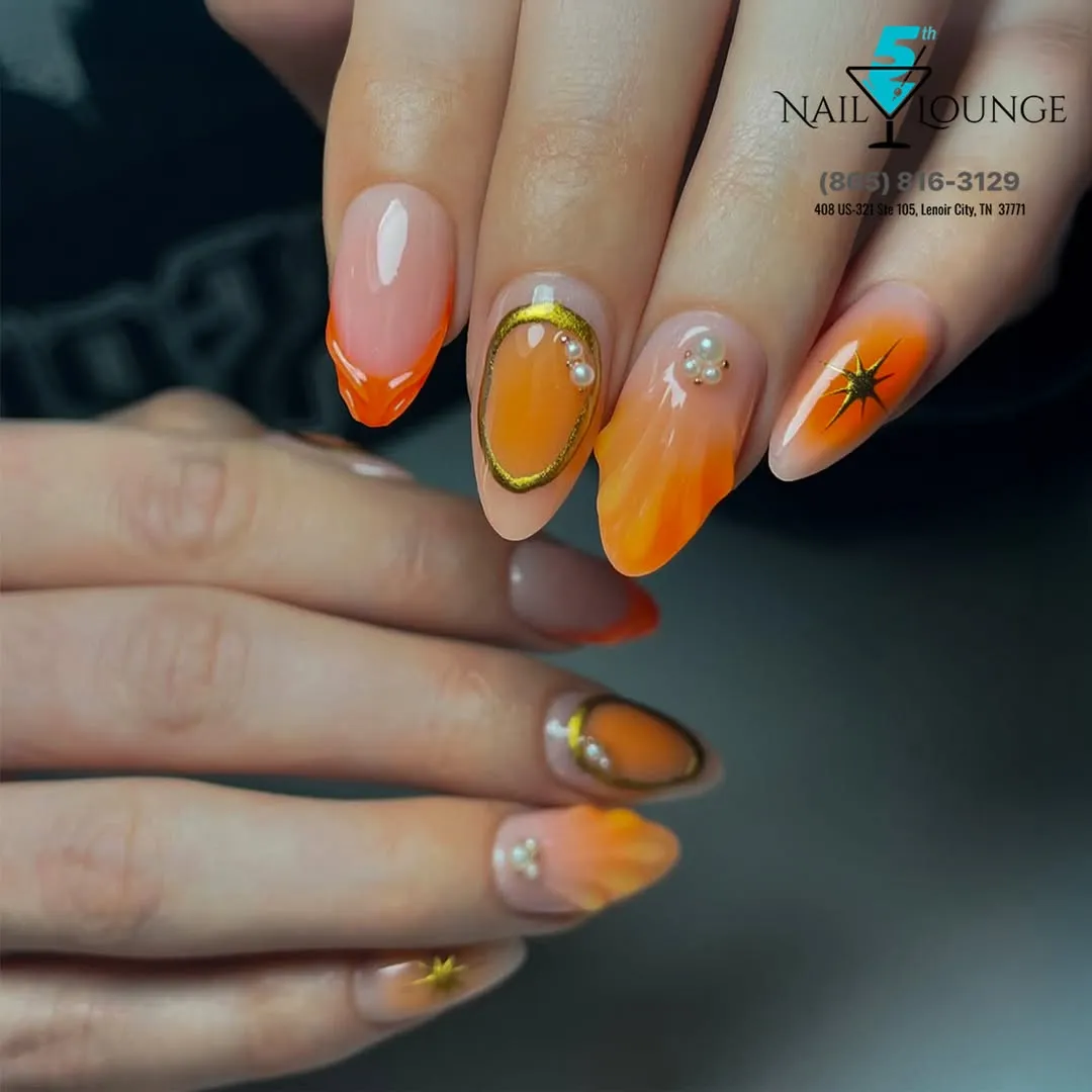 Orange ombrรฉ almonds with gold outline, pearls, and starburst accent