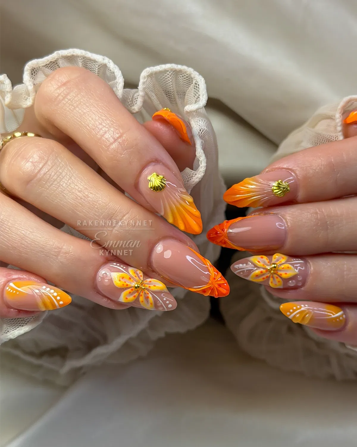 Nude base with orange tips and 3D floral/shell accents