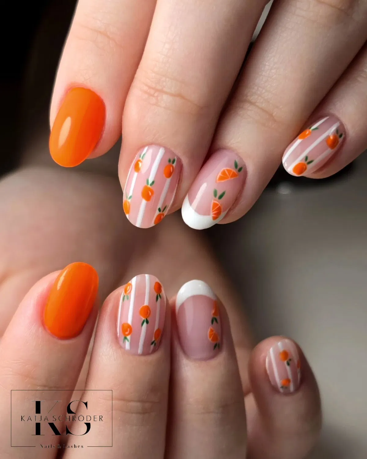 Short orange nails with striped fruit motifs