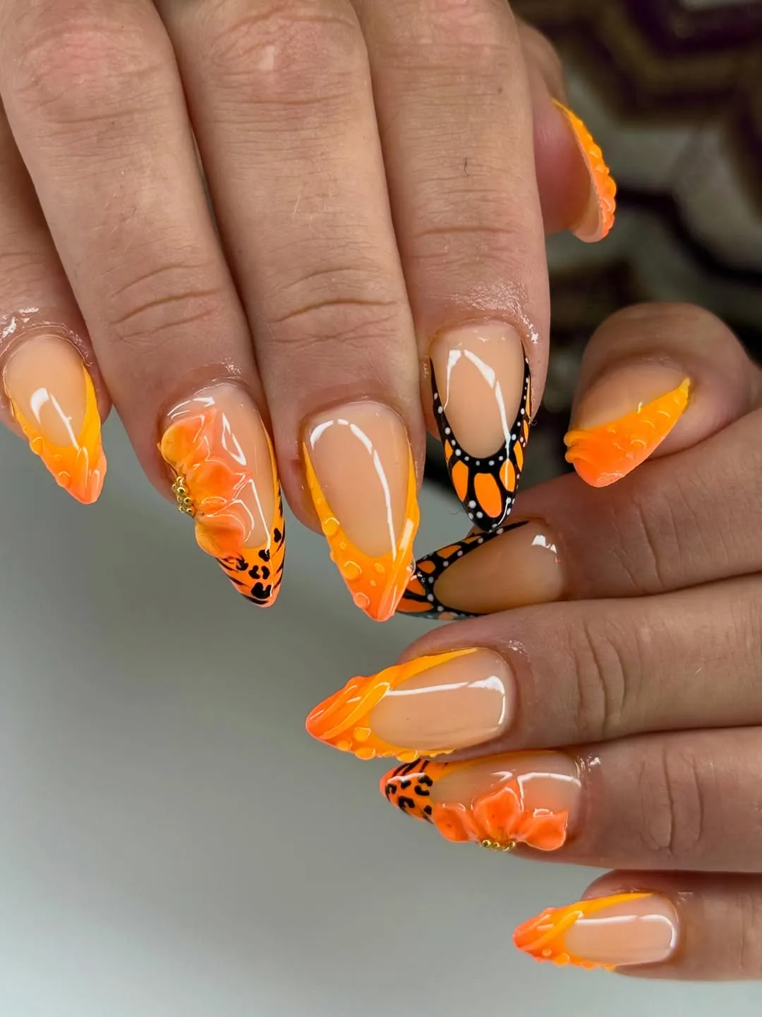 Orange French tips with black patterning and 3D flowers