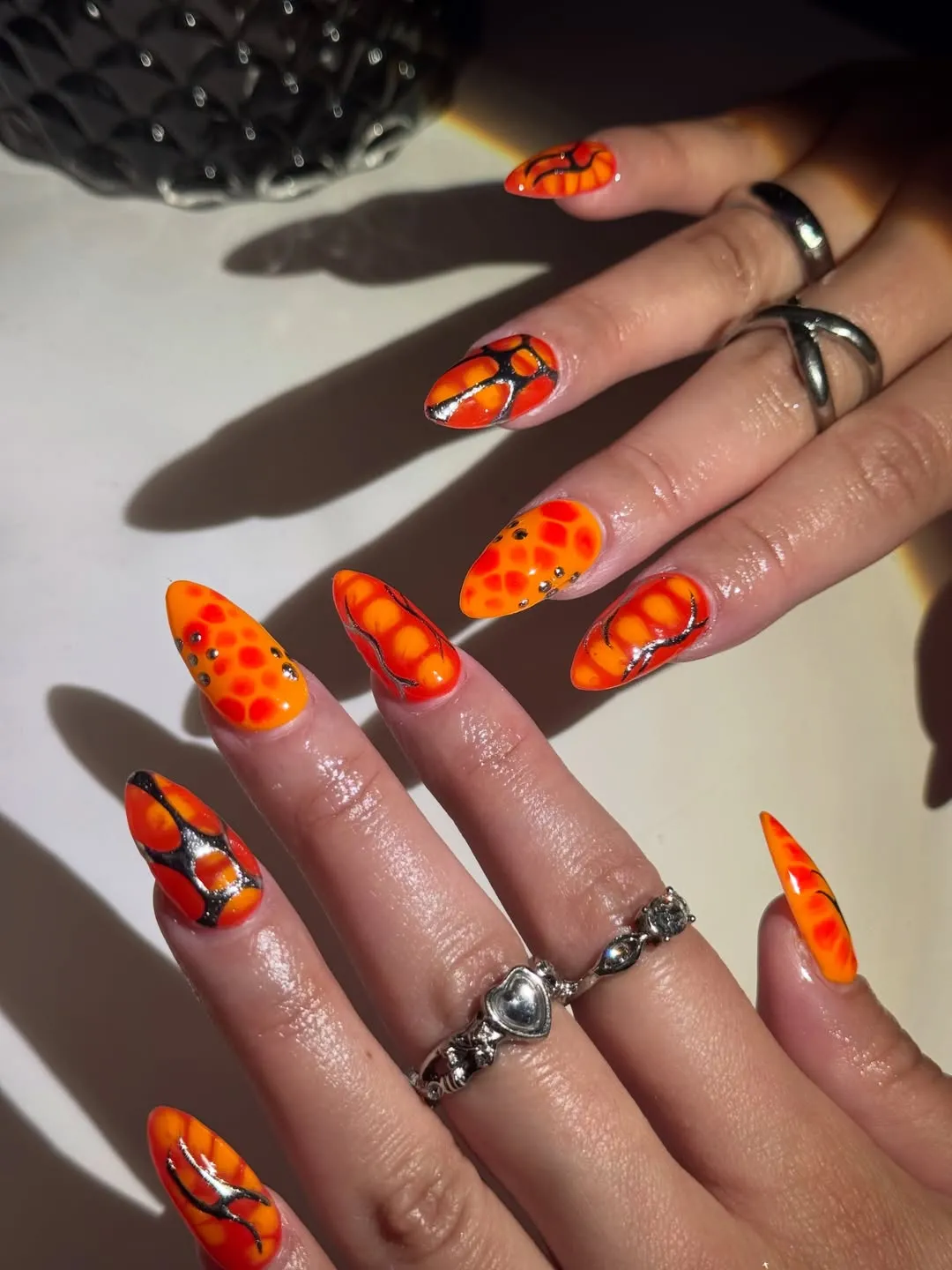 Pointed orange nails with black/silver linework and spots