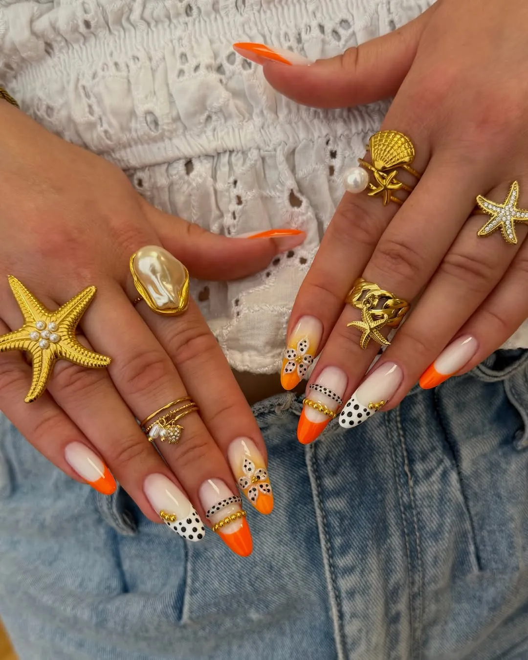 Orange French tips with polka dots and gold bead accents