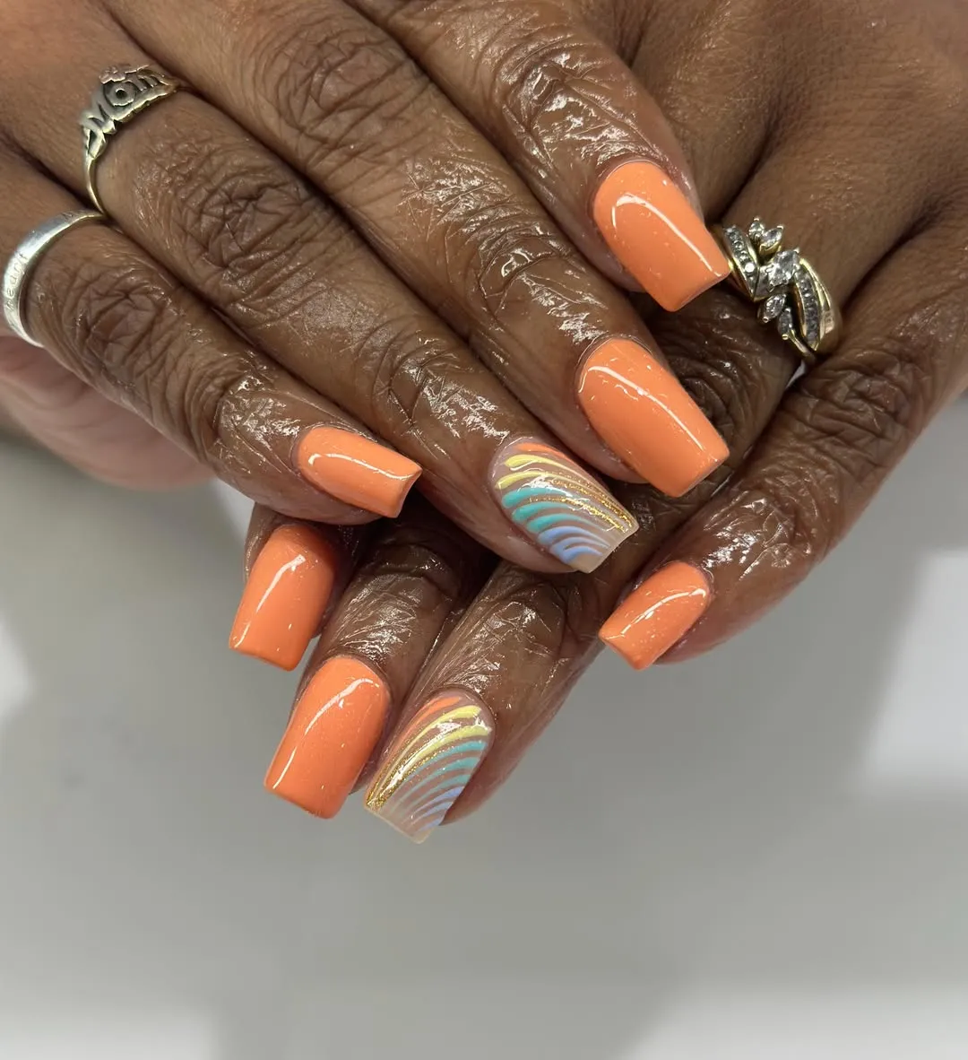 Pastel orange squares with multicolor curved-stripe accent nails