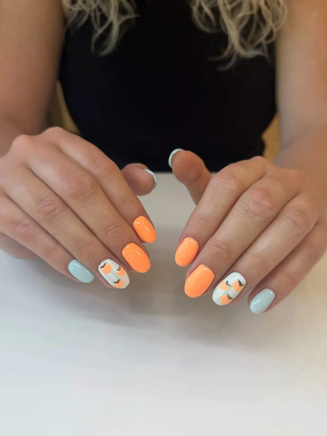 Pastel orange with mint/blue and white accent nails featuring small orange motifs