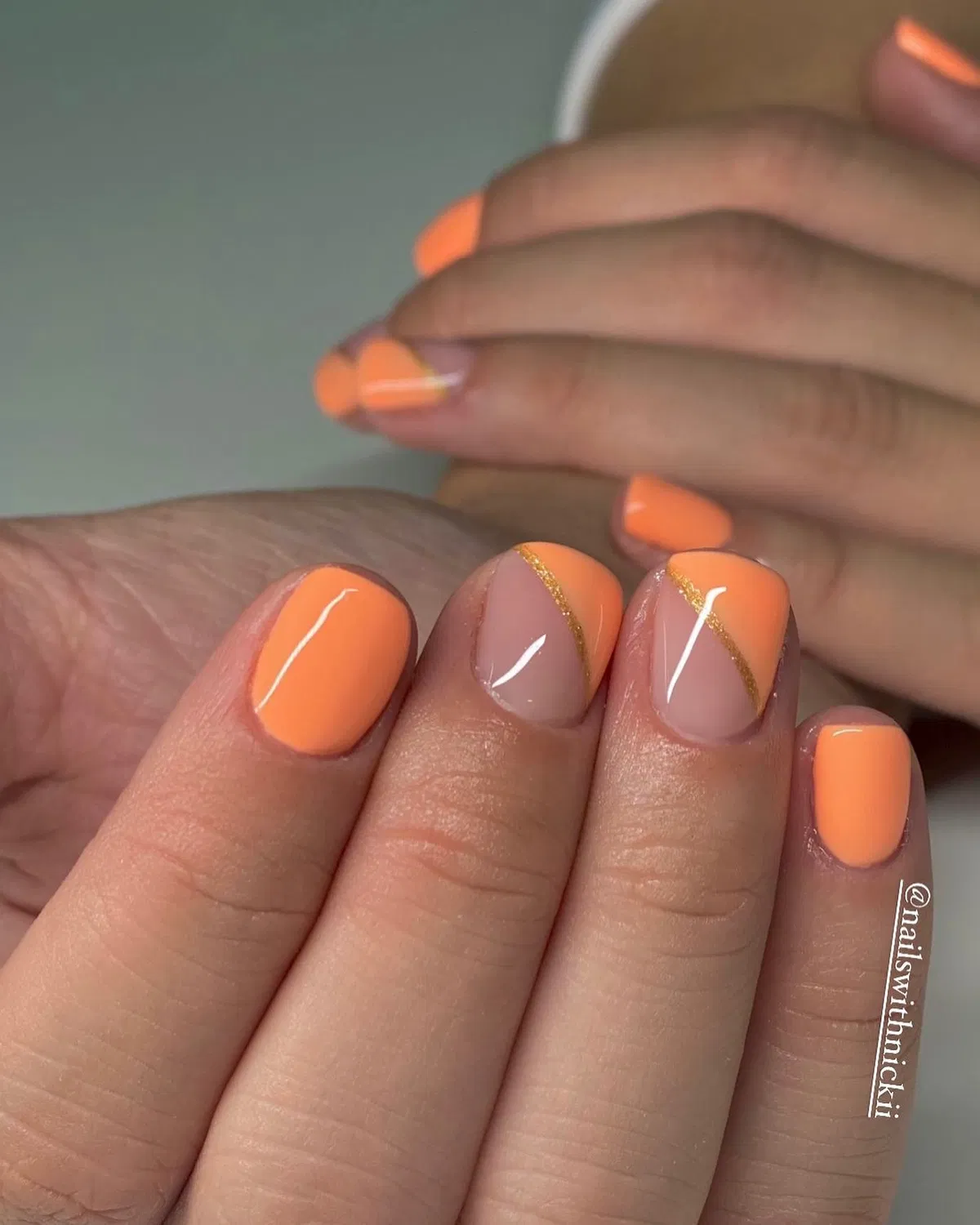 Pastel orange solids with nude-and-gold diagonal accent nails