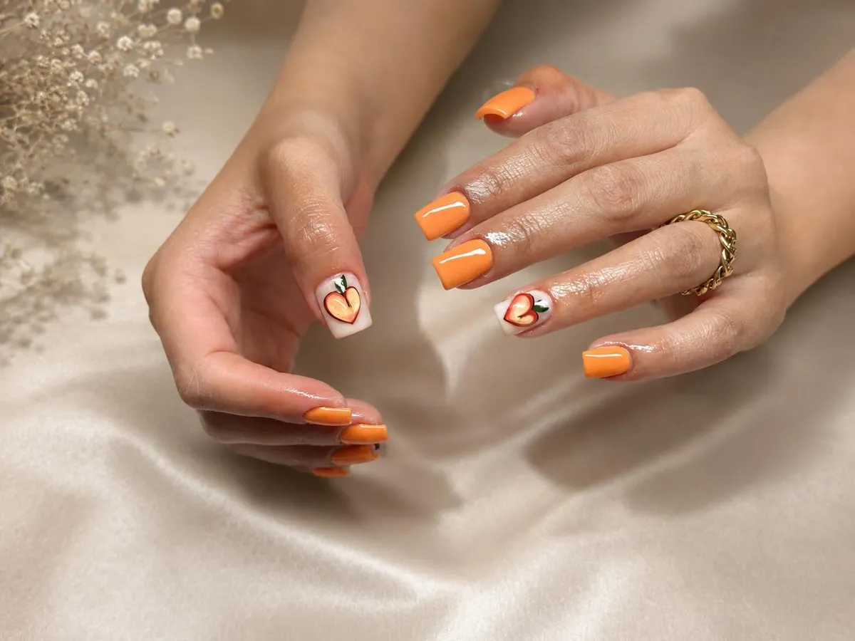 Solid pastel orange with peach illustration accent nails