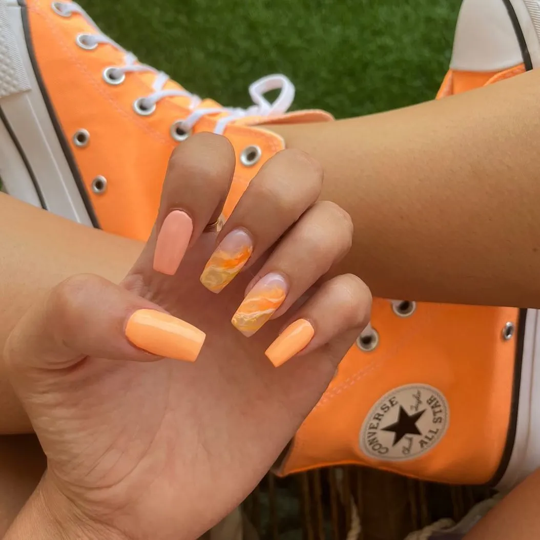 Pastel orange squares with orange-cream marble accent nails