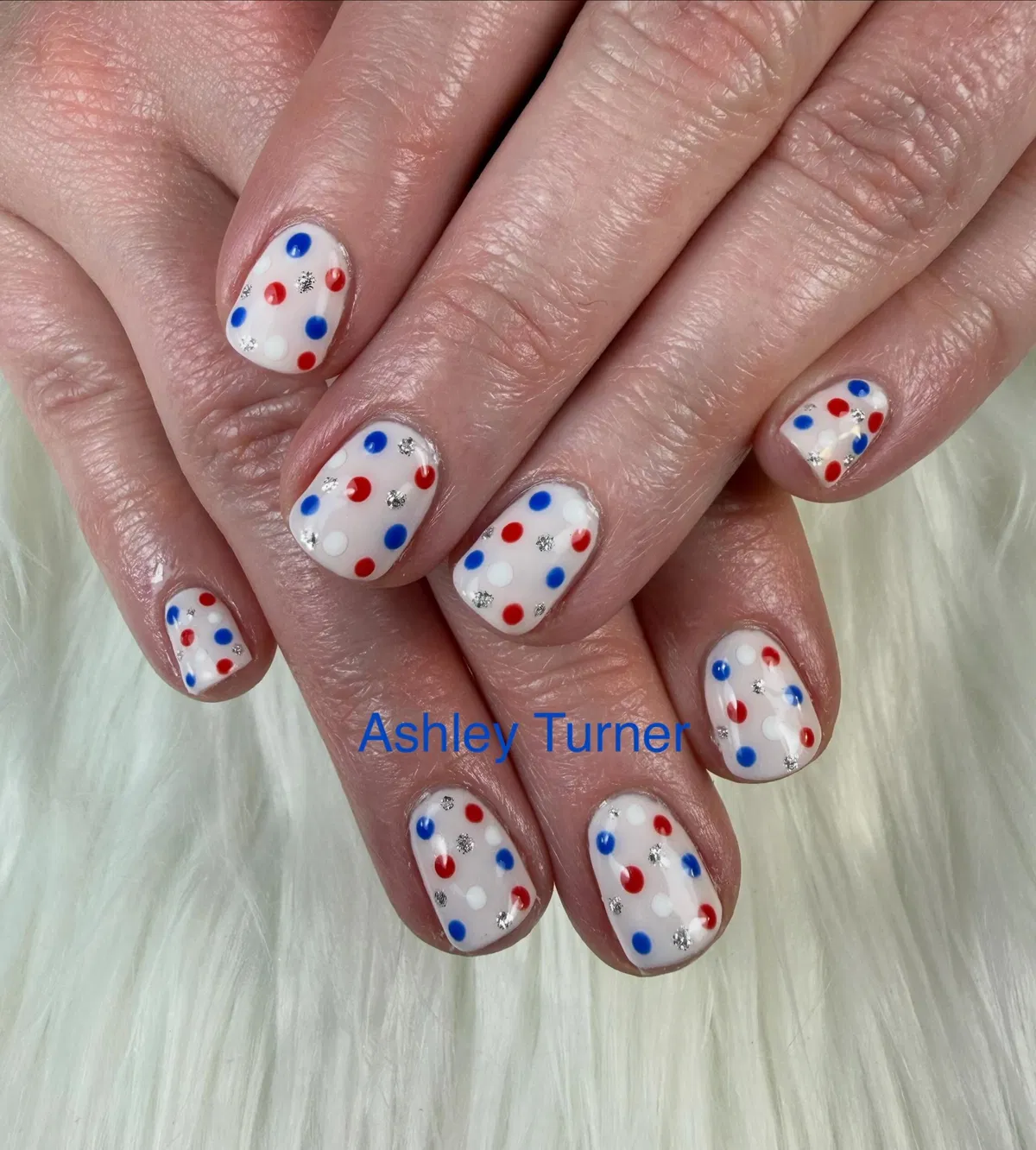 White polka-dot manicure with red/blue dots and silver sparkle