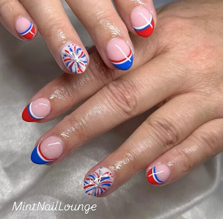 Rounded French tips with red/blue arcs and firework-style accents