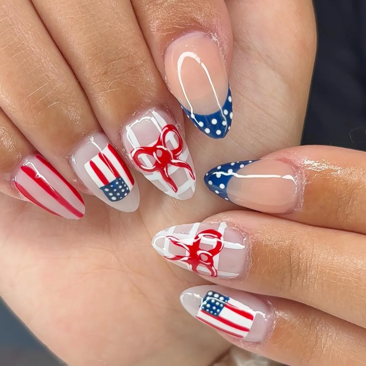 Nude-base almond nails with polka-dot French tips, stripes, and bow accents