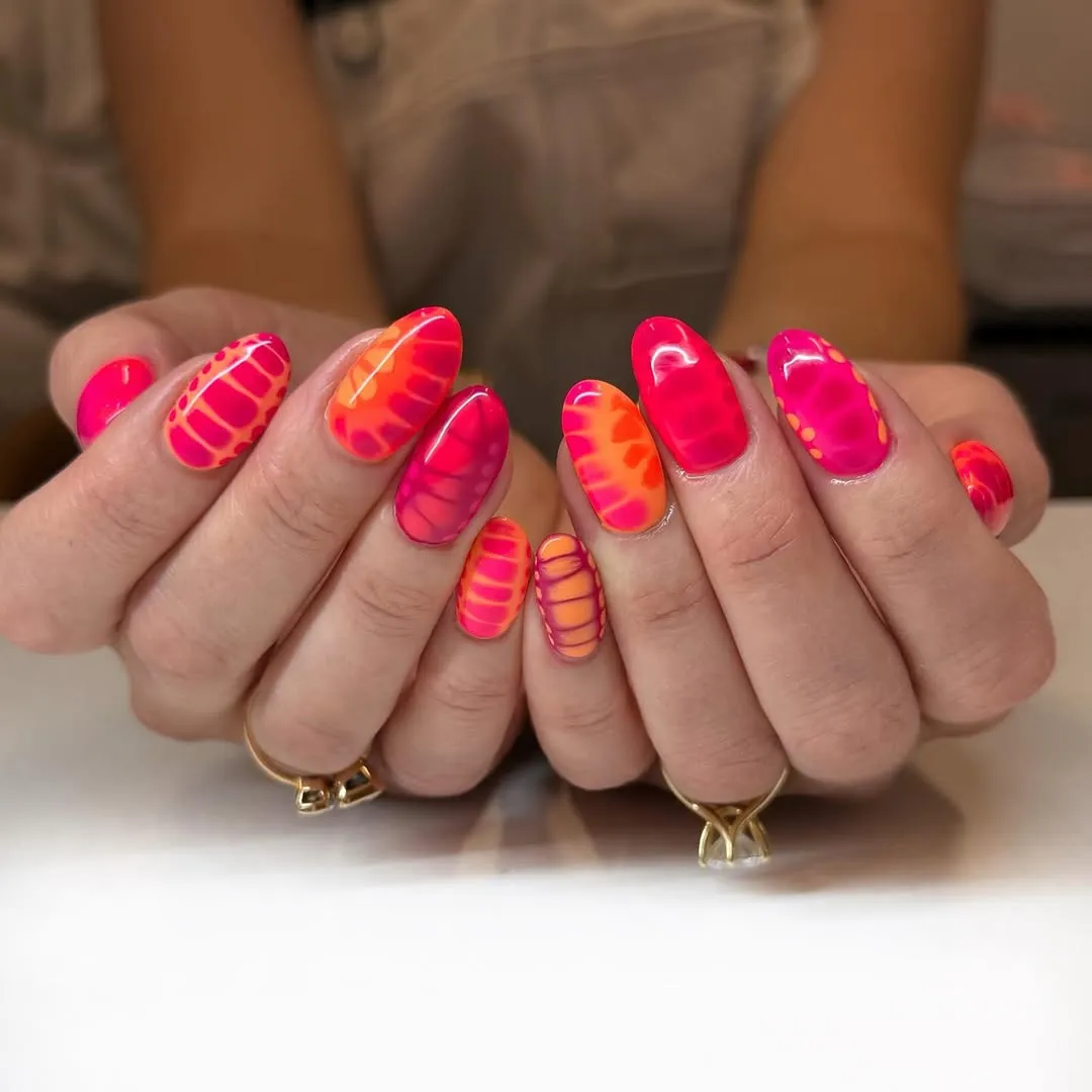 Neon pink-orange scale pattern on oval nails