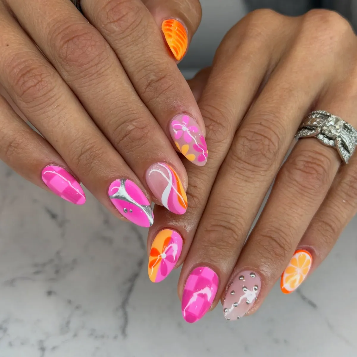 Mixed Pink Orange Nails with studs, floral graphic, and citrus slice