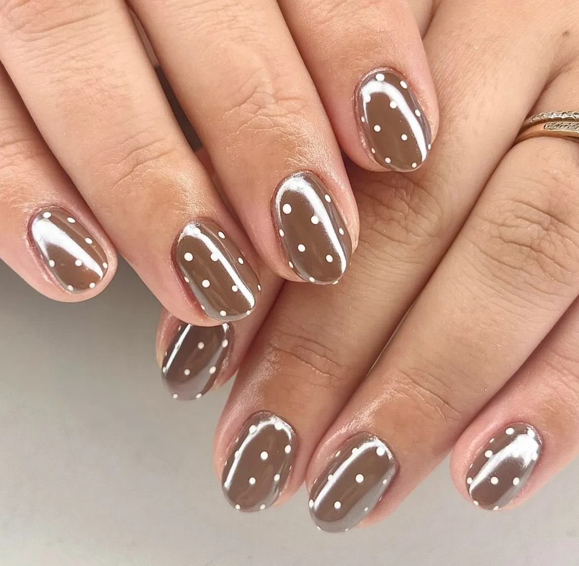 Chocolate-brown glossy nails with white polka dots