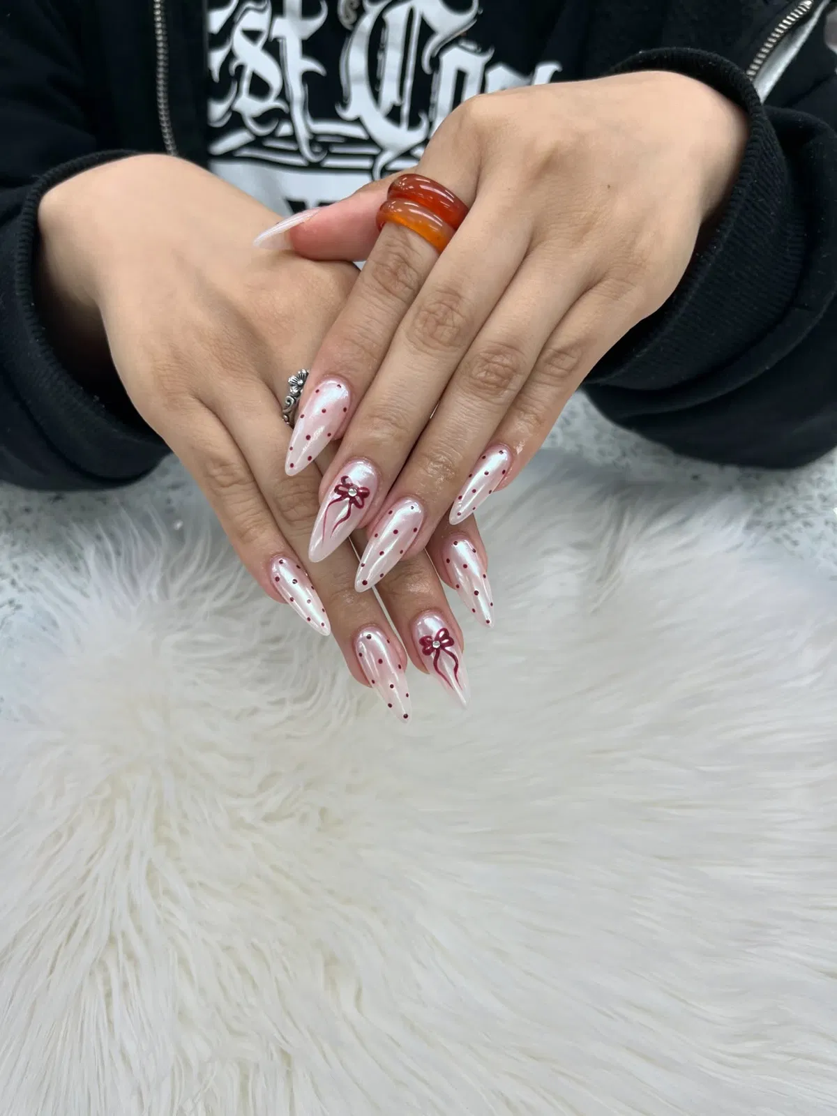 Long pale glossy nails with red dots and bow accents