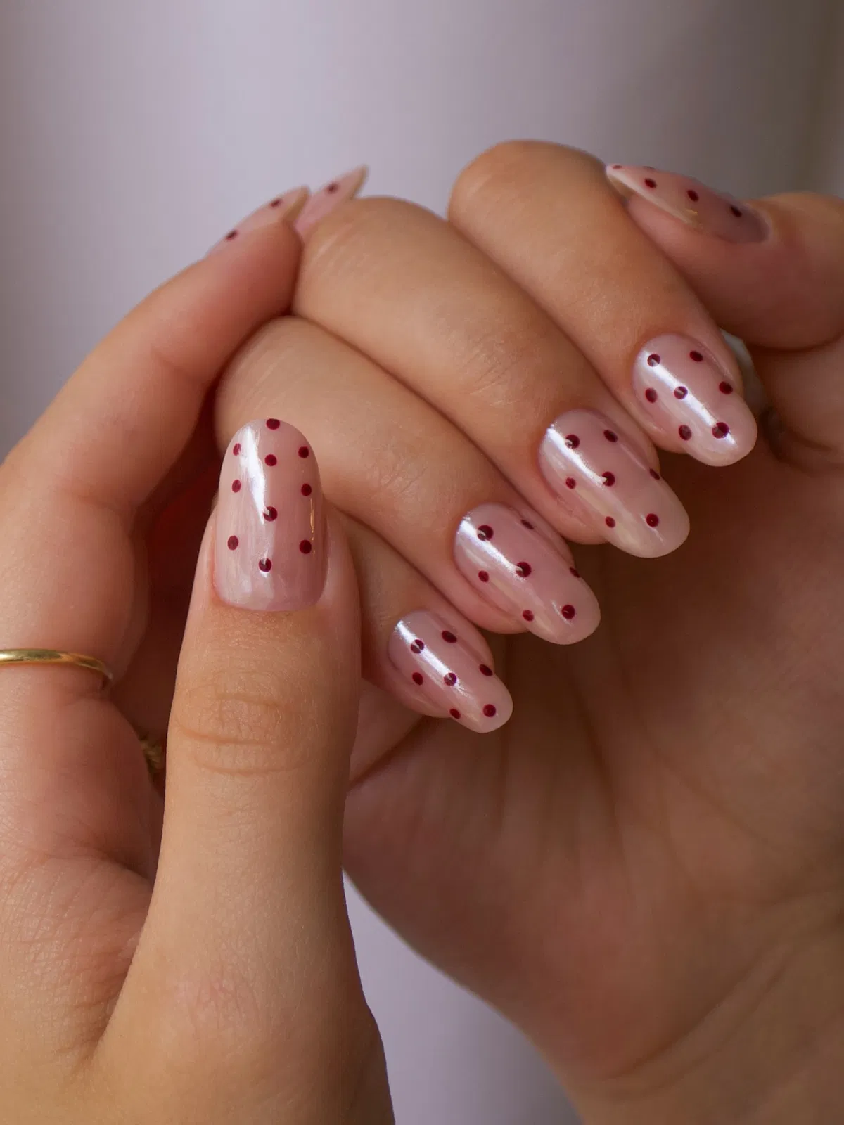 Pale pink glossy nails with red polka dots