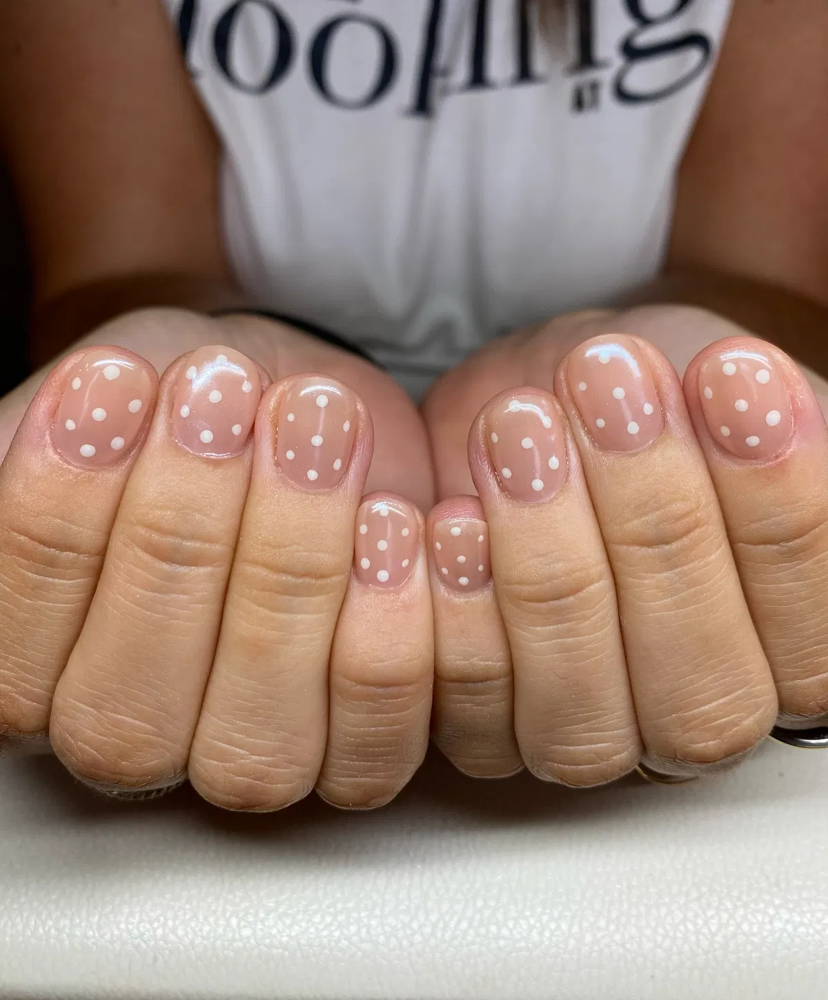 Short sheer nude nails with white polka dots