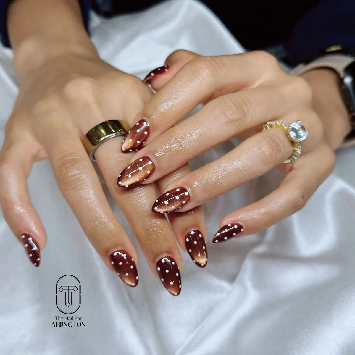 Long brown almond nails with white polka dots and curved lines