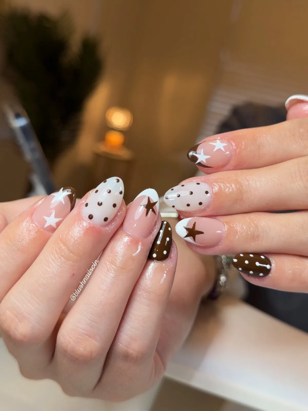 Brown-tipped nude nails with polka dots and star accents