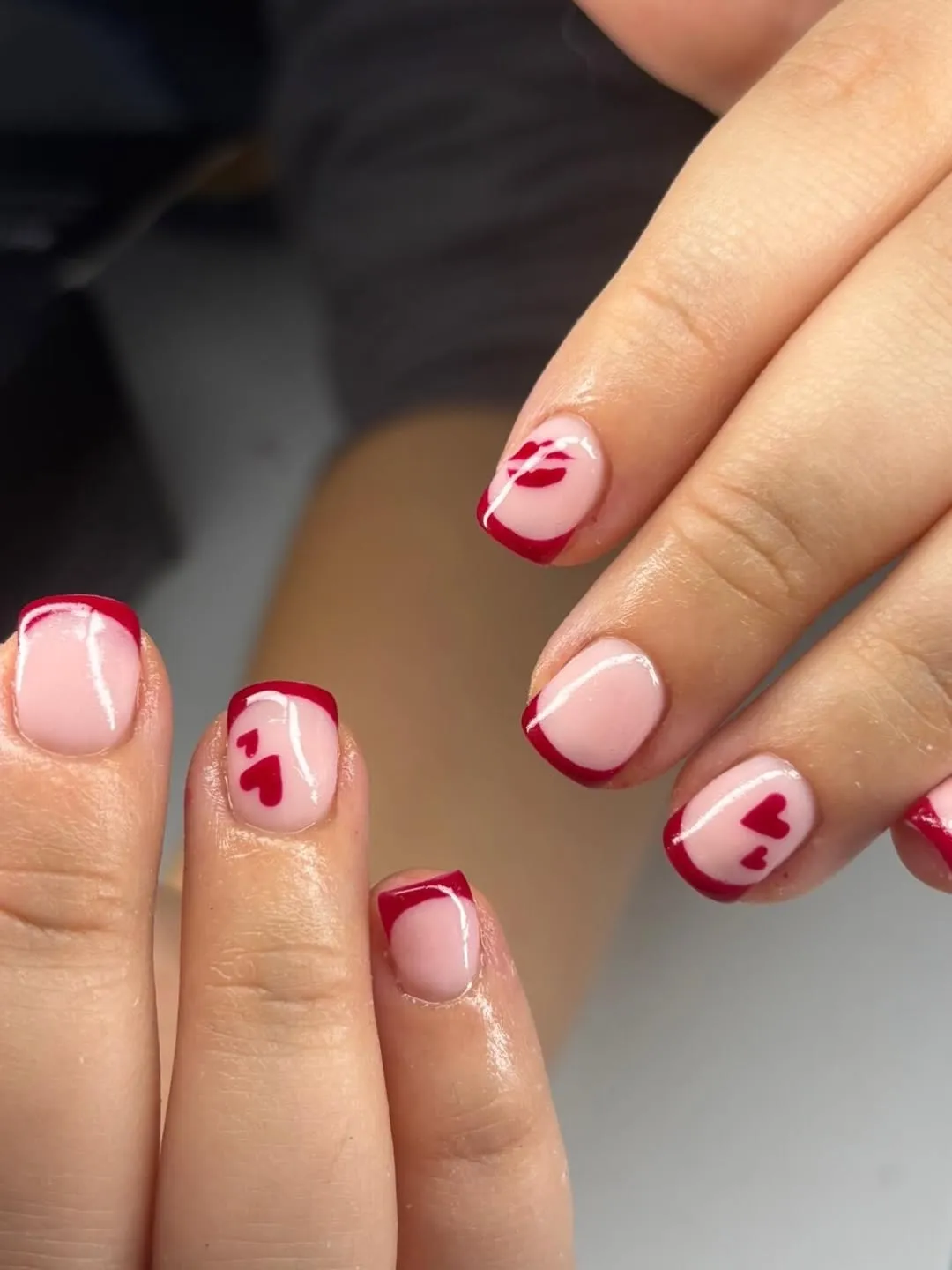 Short red French tips with hearts and lip-print accents
