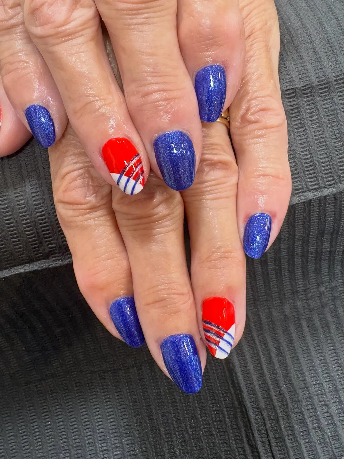 Sparkly blue nails with red-and-striped diagonal accents