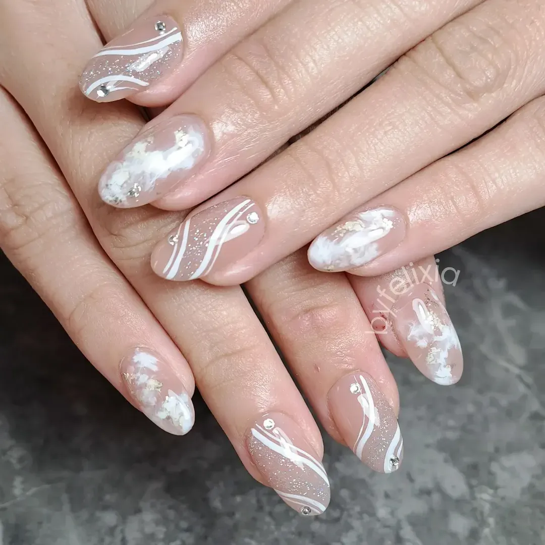 Glossy nude nails with white wave lines, cloud accents, and sparkle