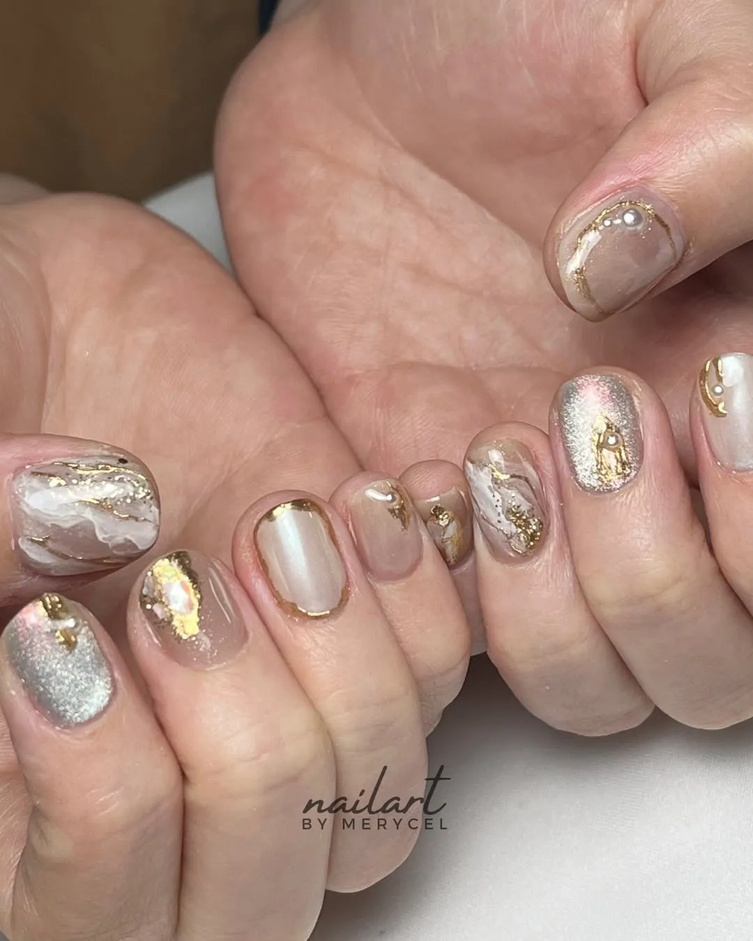 Mixed nude, milky white, and silver nails with gold outlining and marbling