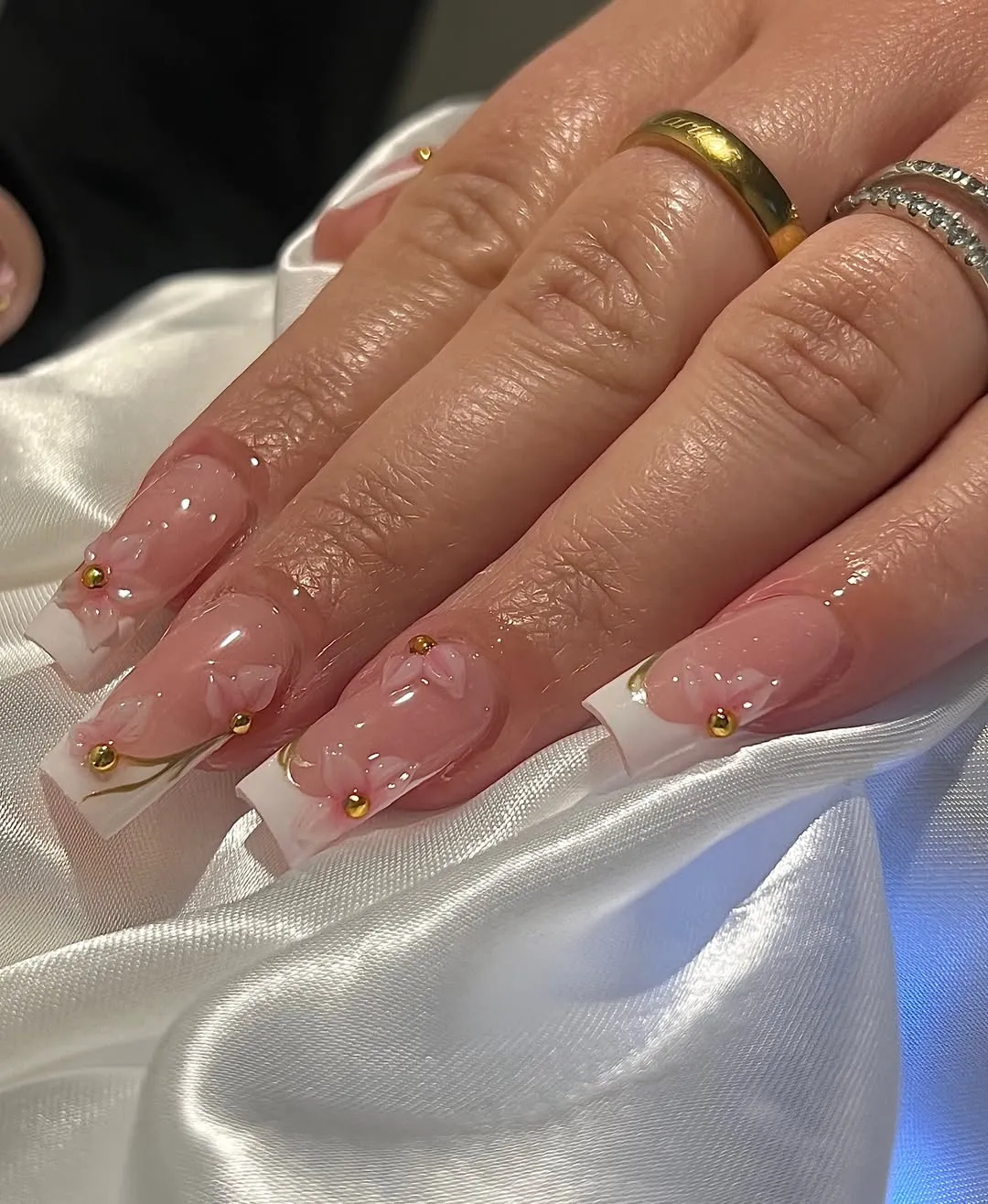 Pink-and-white square French tips with raised florals and gold studs