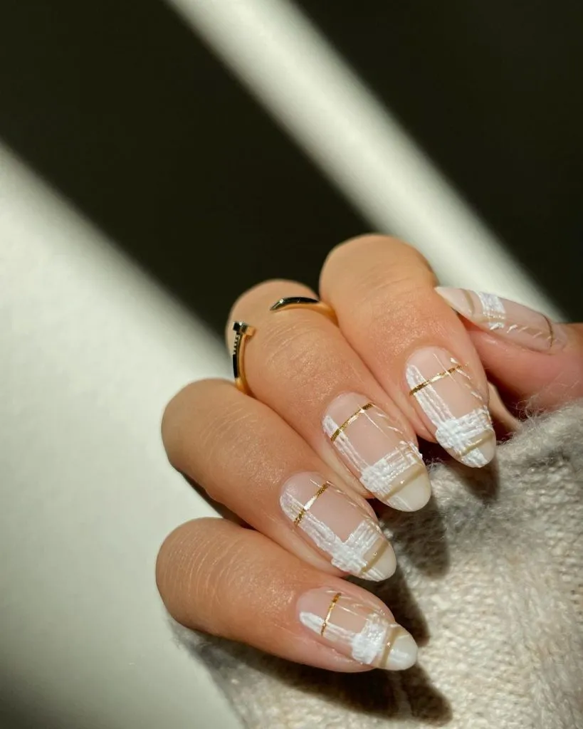 Nude oval nails with white textured plaid and gold striping