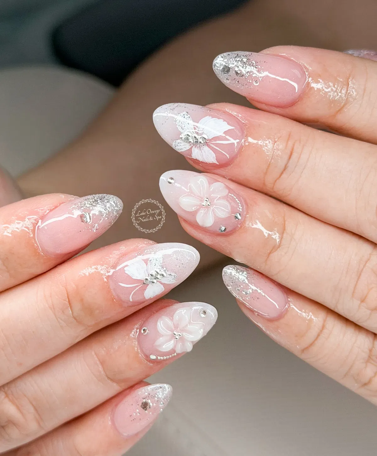 Pink almond nails with silver glitter tips and white floral accents