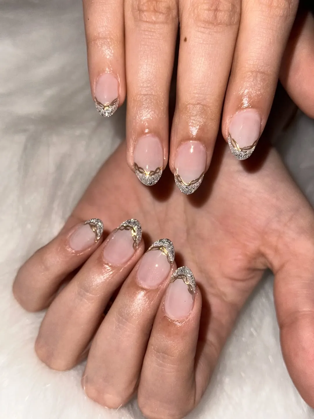 Oval pink nails with silver glitter tips and gold wave line