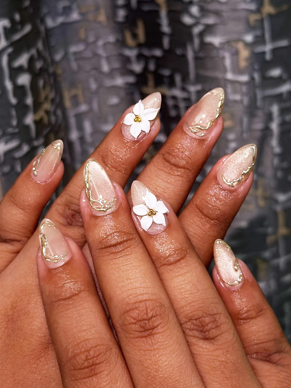 Shimmery champagne nails with gold edging and 3D white flowers