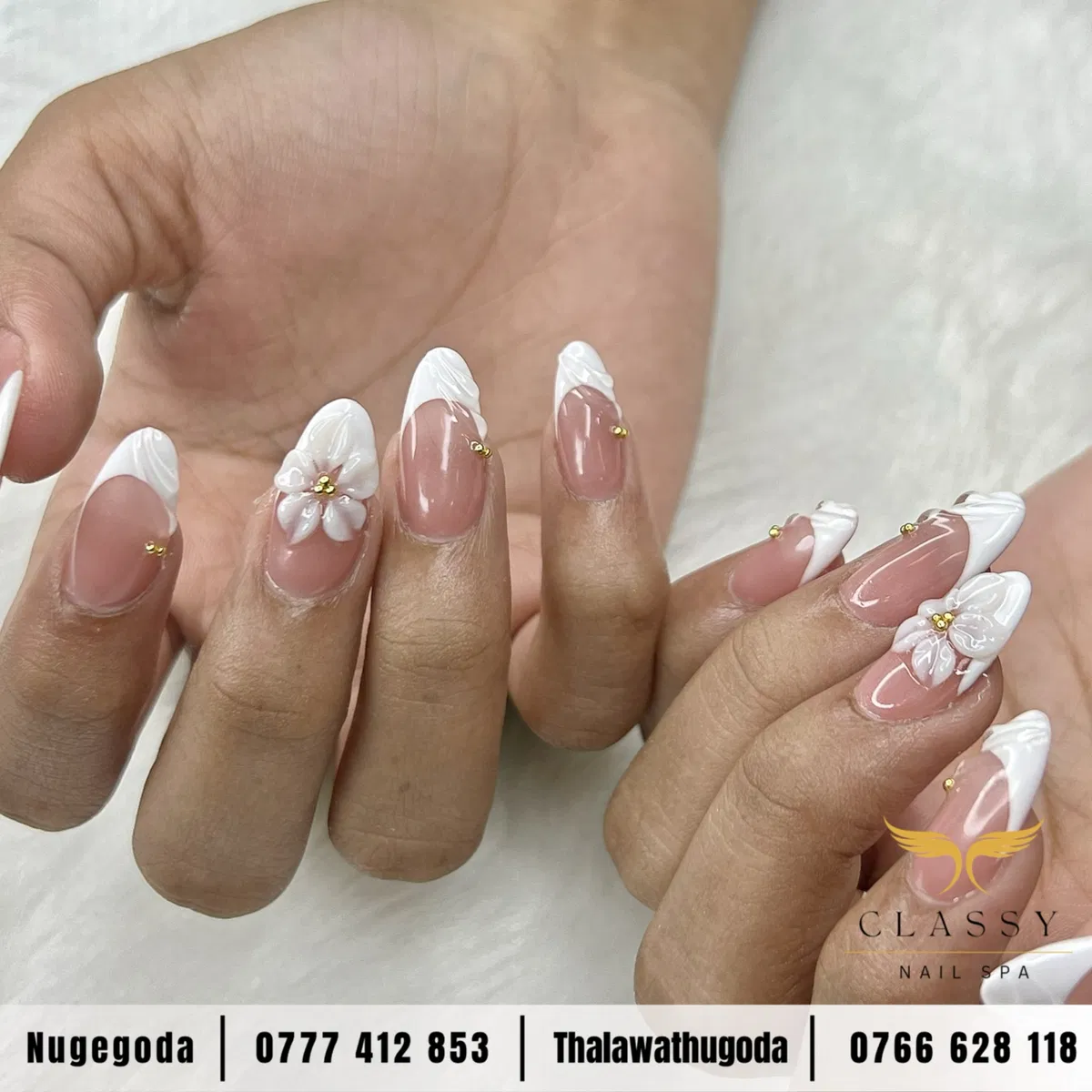 Nude-pink almond French tips with raised white detail and gold beads