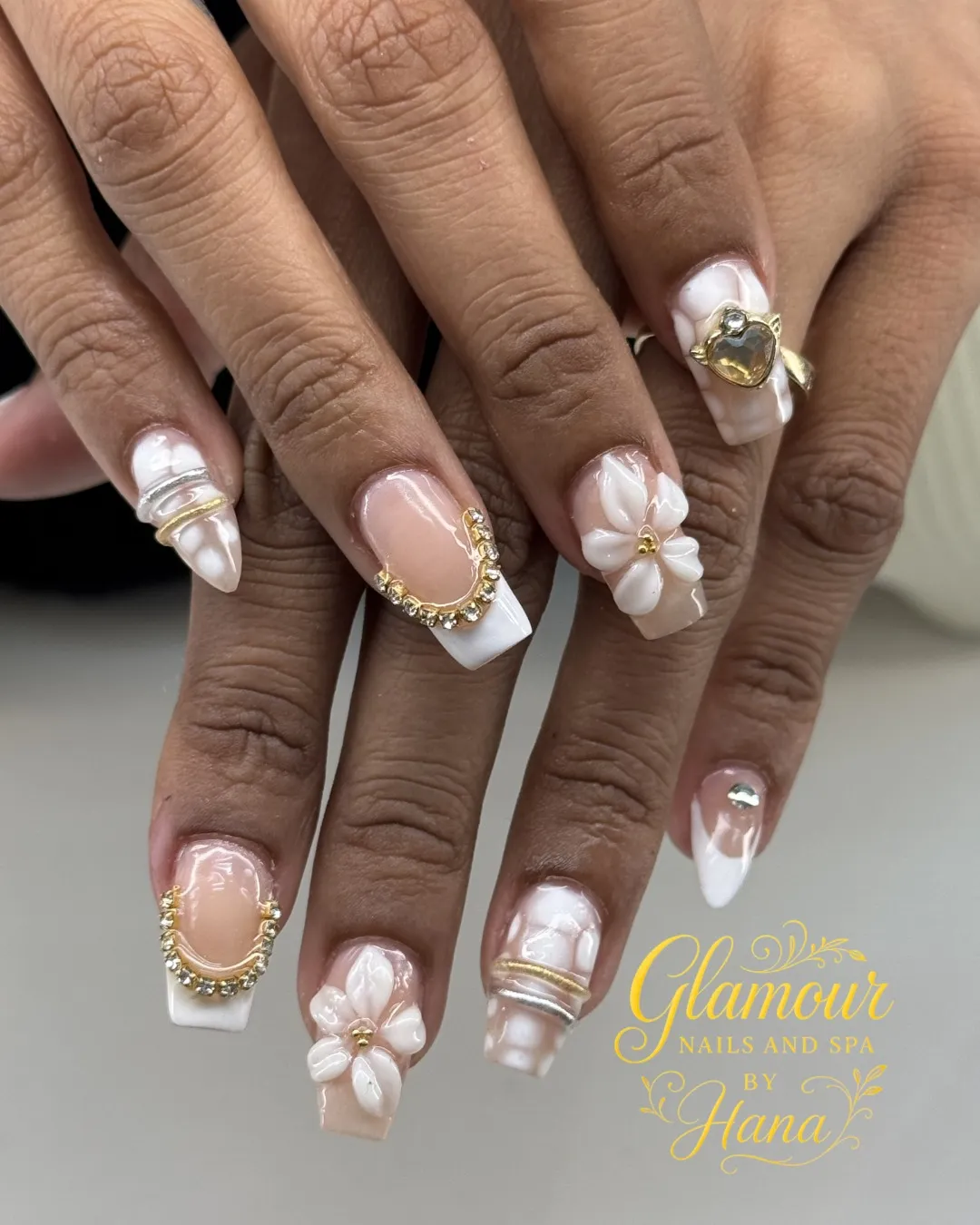 Nude-pink French tips with curved frames, rhinestones, and 3D flowers (watermarked)