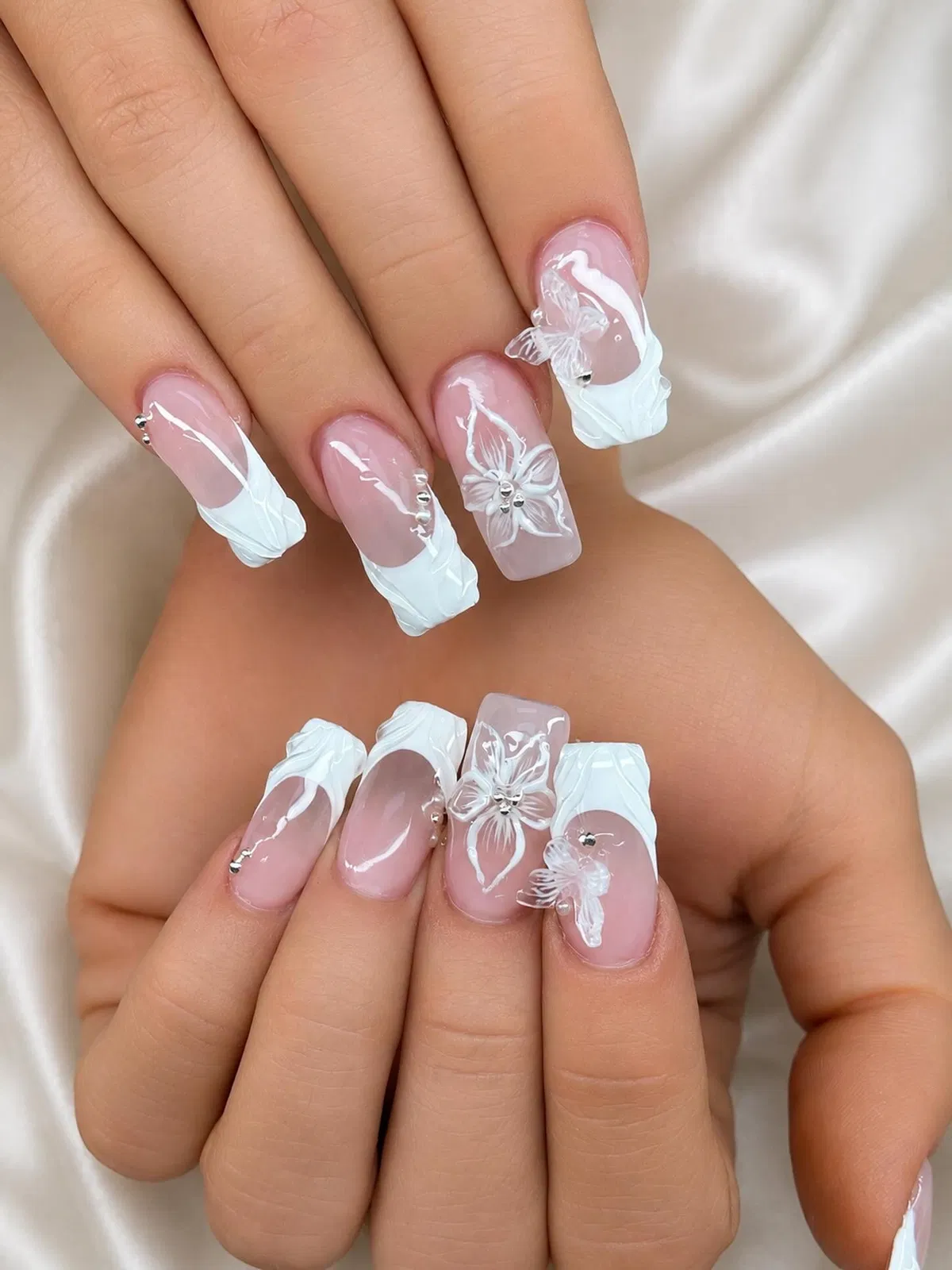 Square pink nails with sculpted white French tips and 3D florals
