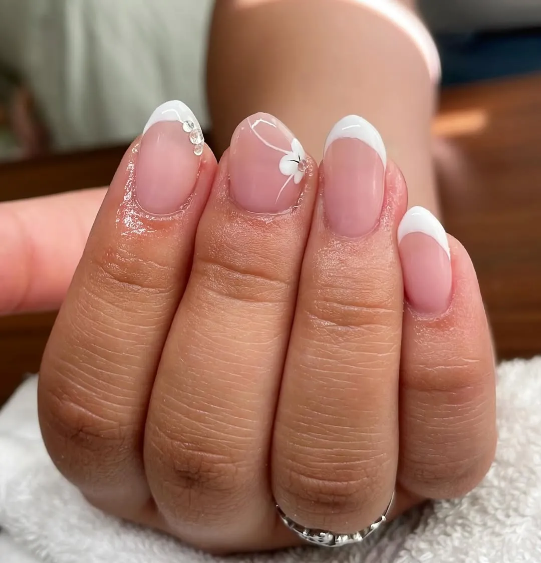 Classic short French tips with subtle floral and rhinestones