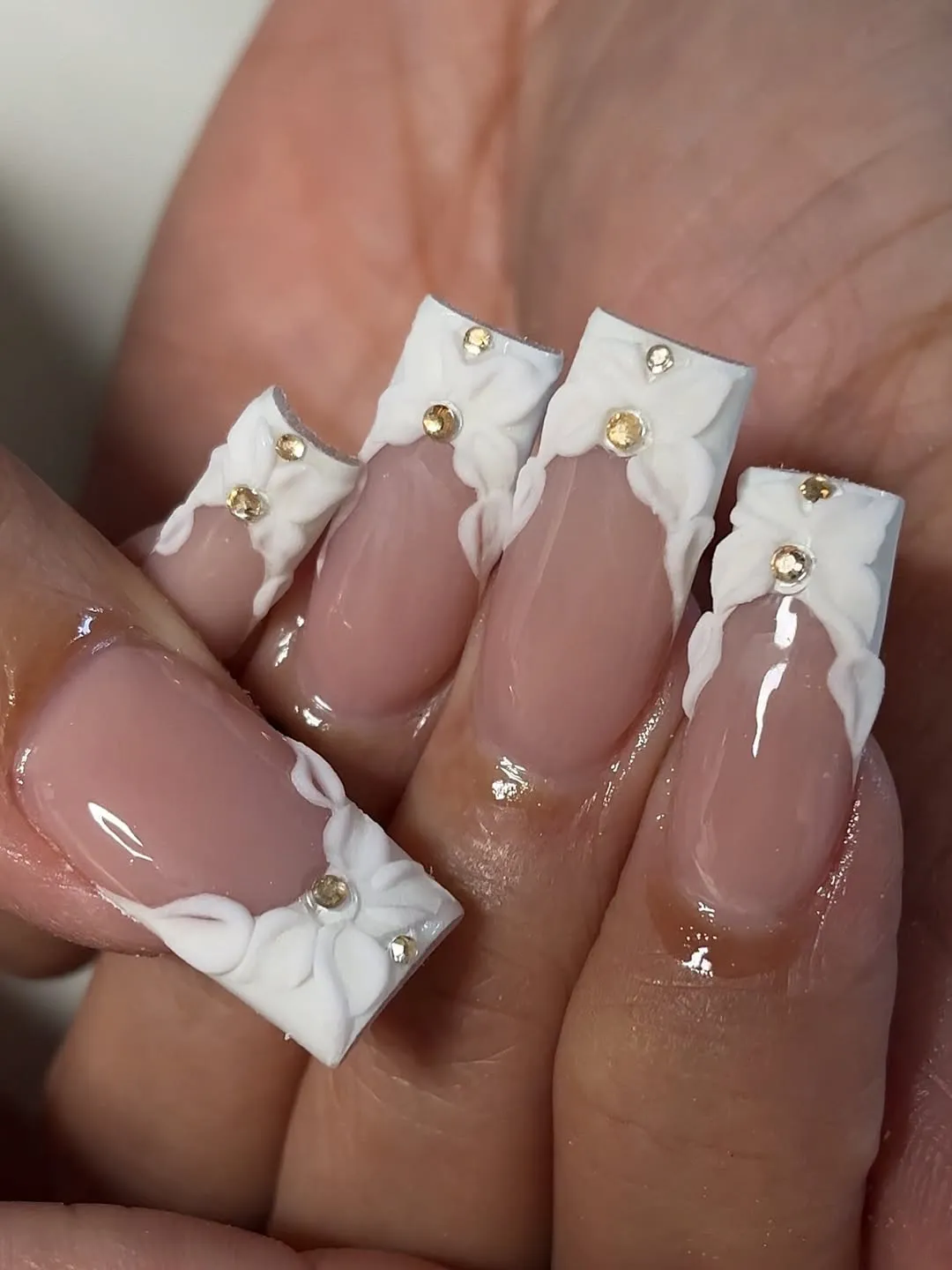 Bold white French tips with textured floral edges and gold-toned studs