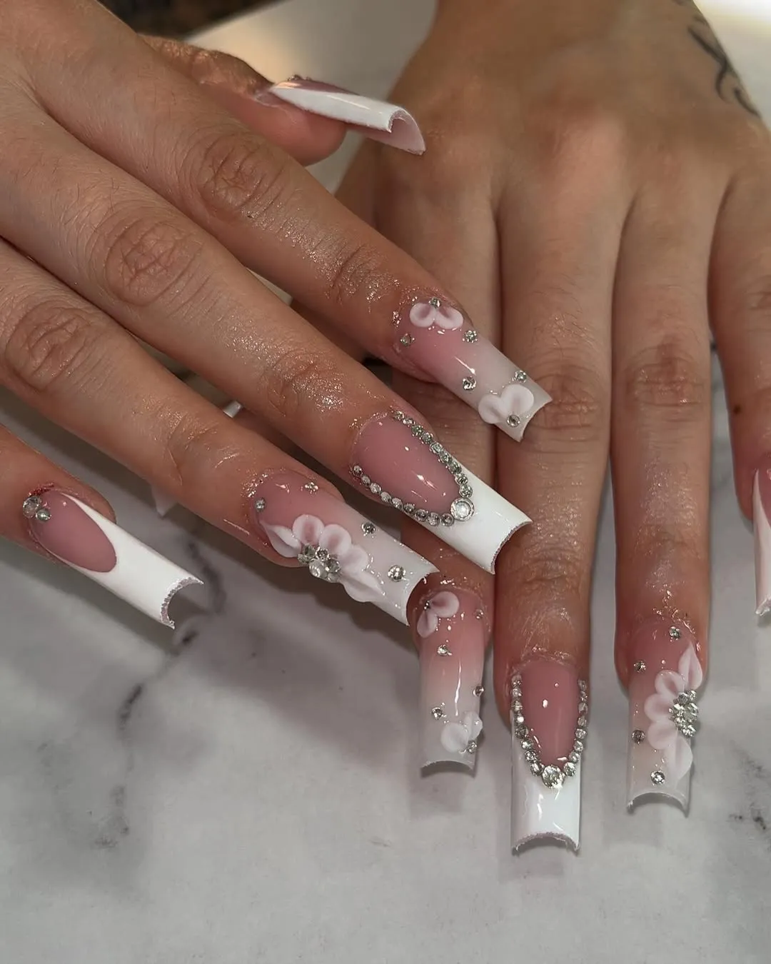 Extra-glam French tips with rhinestone frames and white floral accents