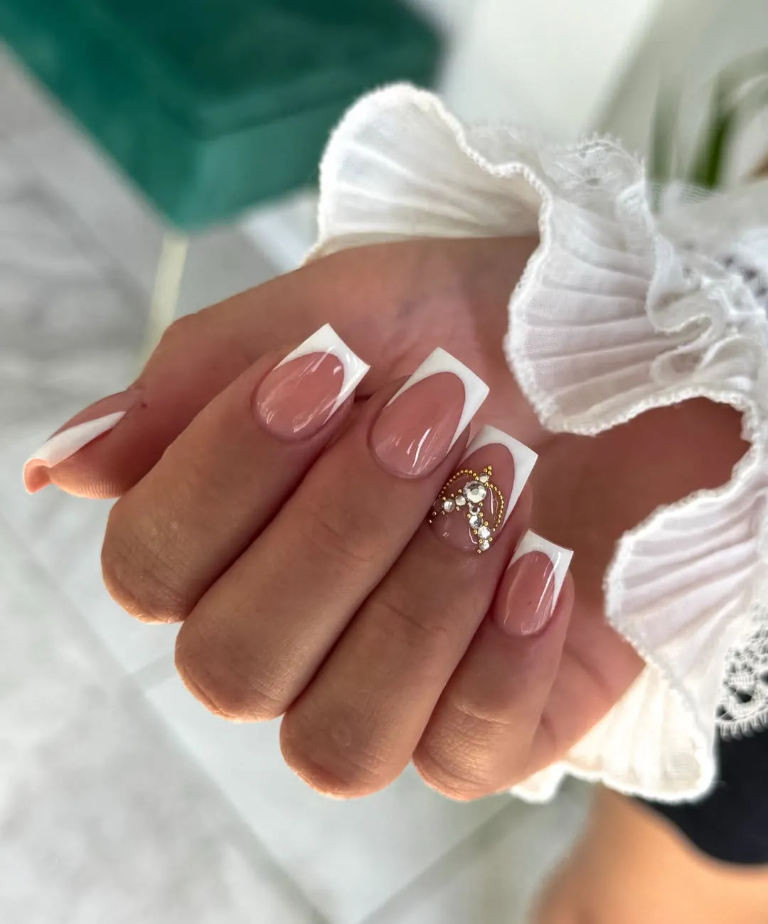 Short geometric French tips with a gold-and-rhinestone accent cluster