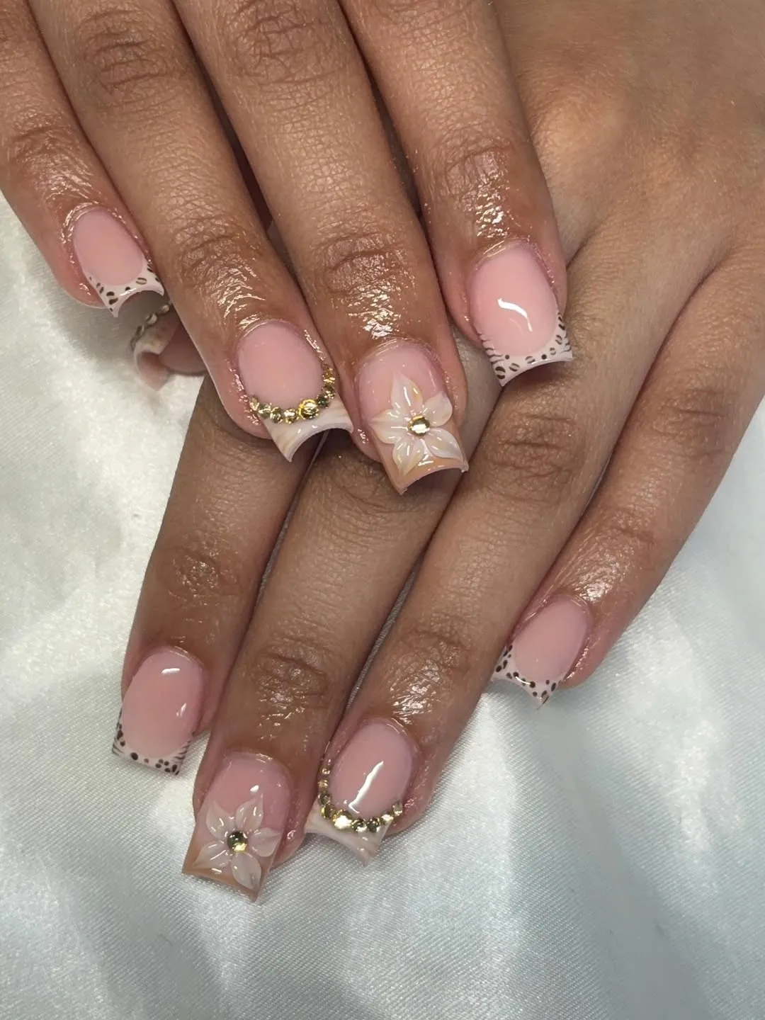 Spotted French tips with a translucent flower accent and gold-toned details
