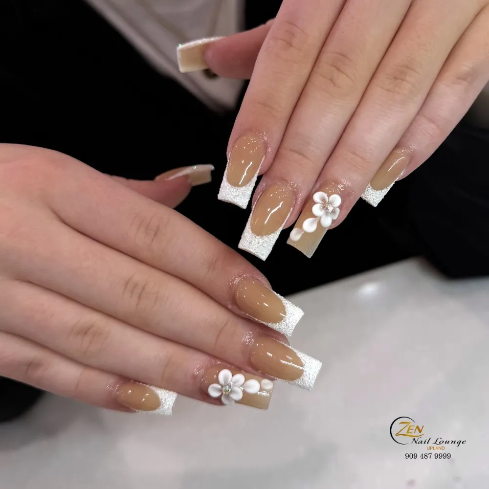 Tan nude nails with textured white tips and raised flower accents