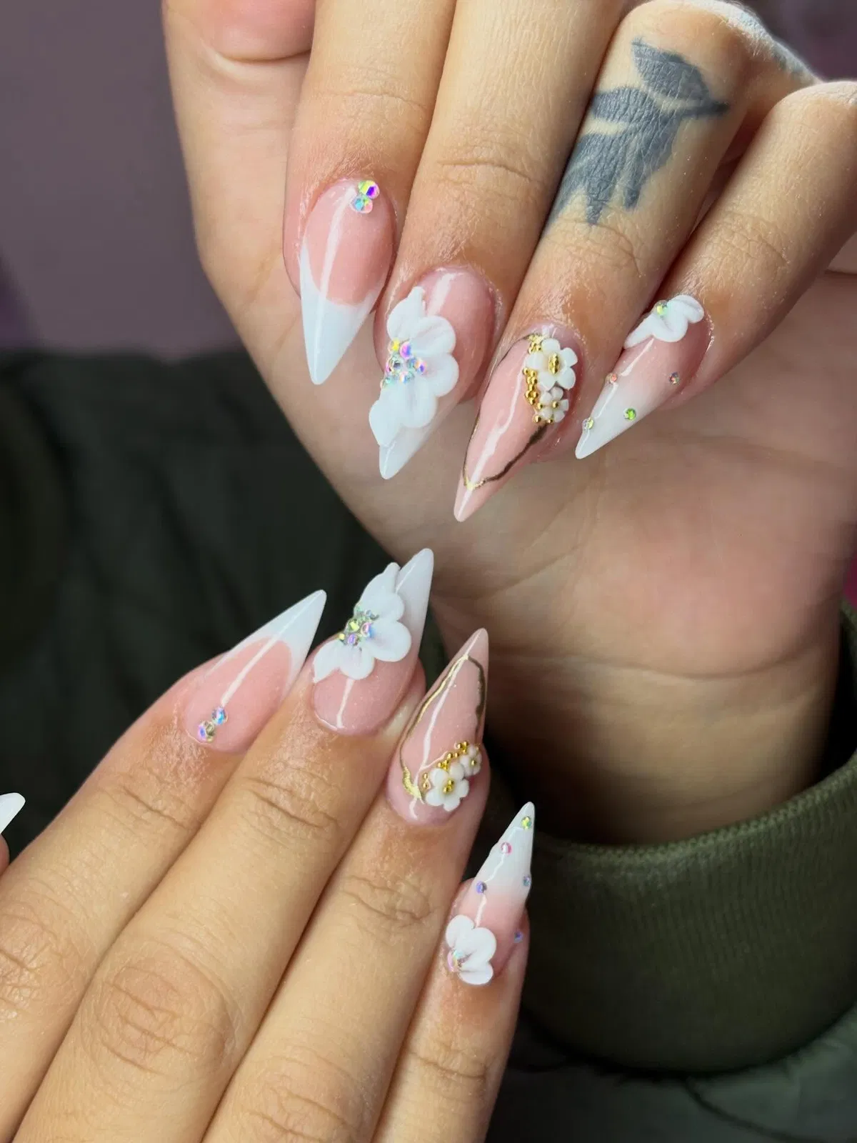 Stiletto French tips with 3D flowers, rhinestones, and gold accents