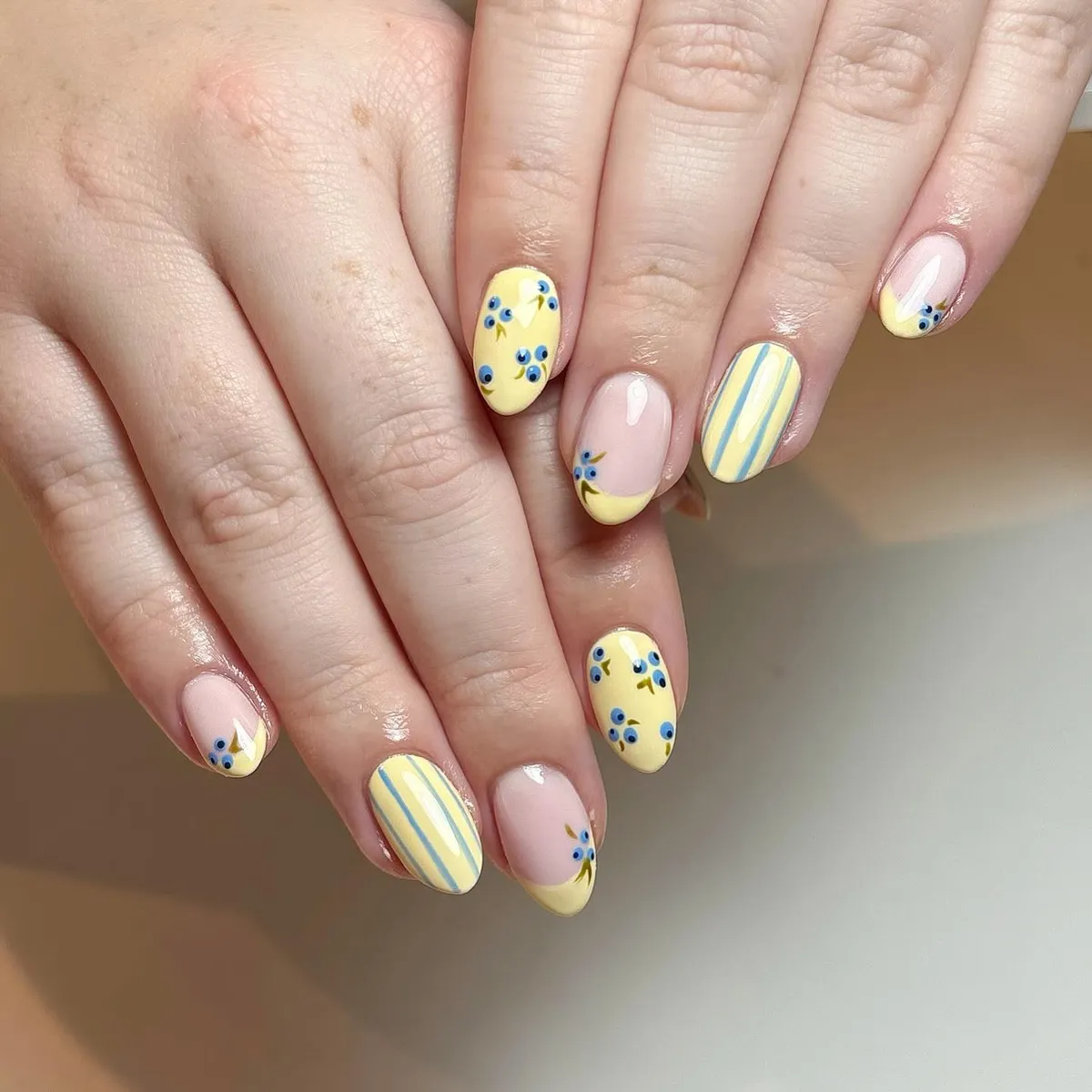 Yellow French tips with blue floral details and striped accent